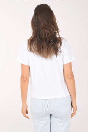 Woman wearing a white t-shirt with a graphic design on a plain background