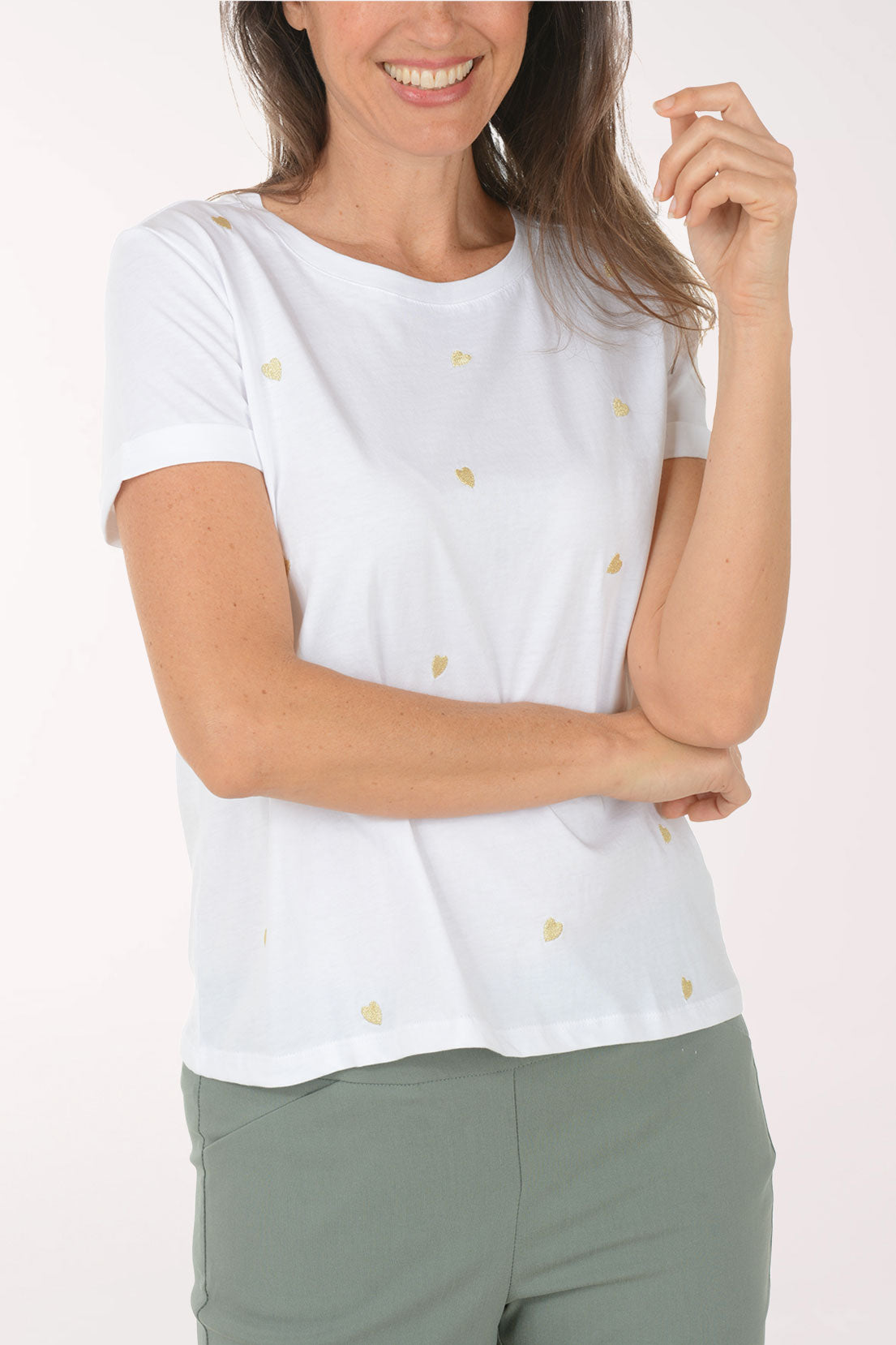 Woman wearing a white t-shirt with a heart pattern and green pants on a white background