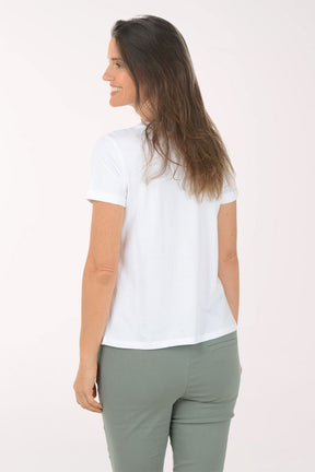 Woman wearing a white t-shirt with a heart pattern and green pants on a white background