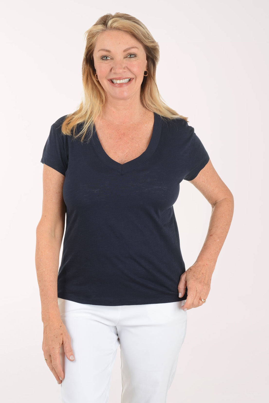 Woman wearing a navy blue t-shirt and white pants on a white background