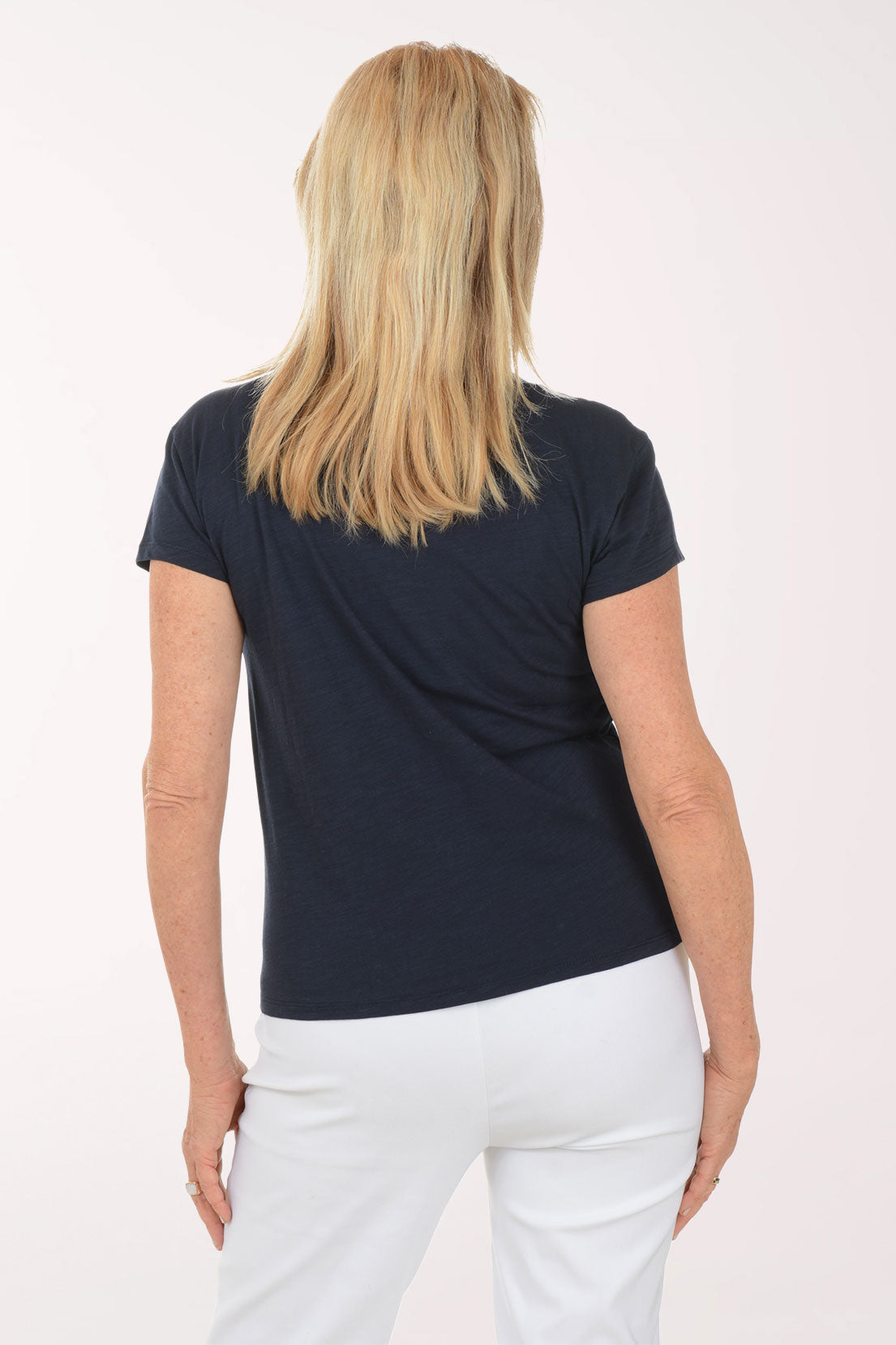 Woman wearing a navy blue t-shirt and white pants on a white background