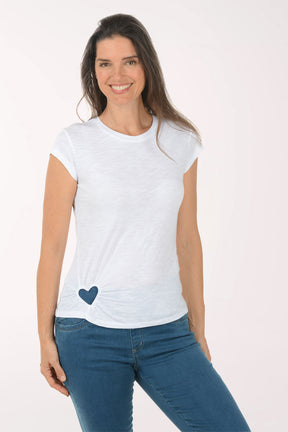 Woman wearing a white t-shirt with a blue heart design and blue jeans on a white background