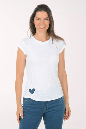 Woman wearing a white t-shirt with a blue heart design and blue jeans on a white background