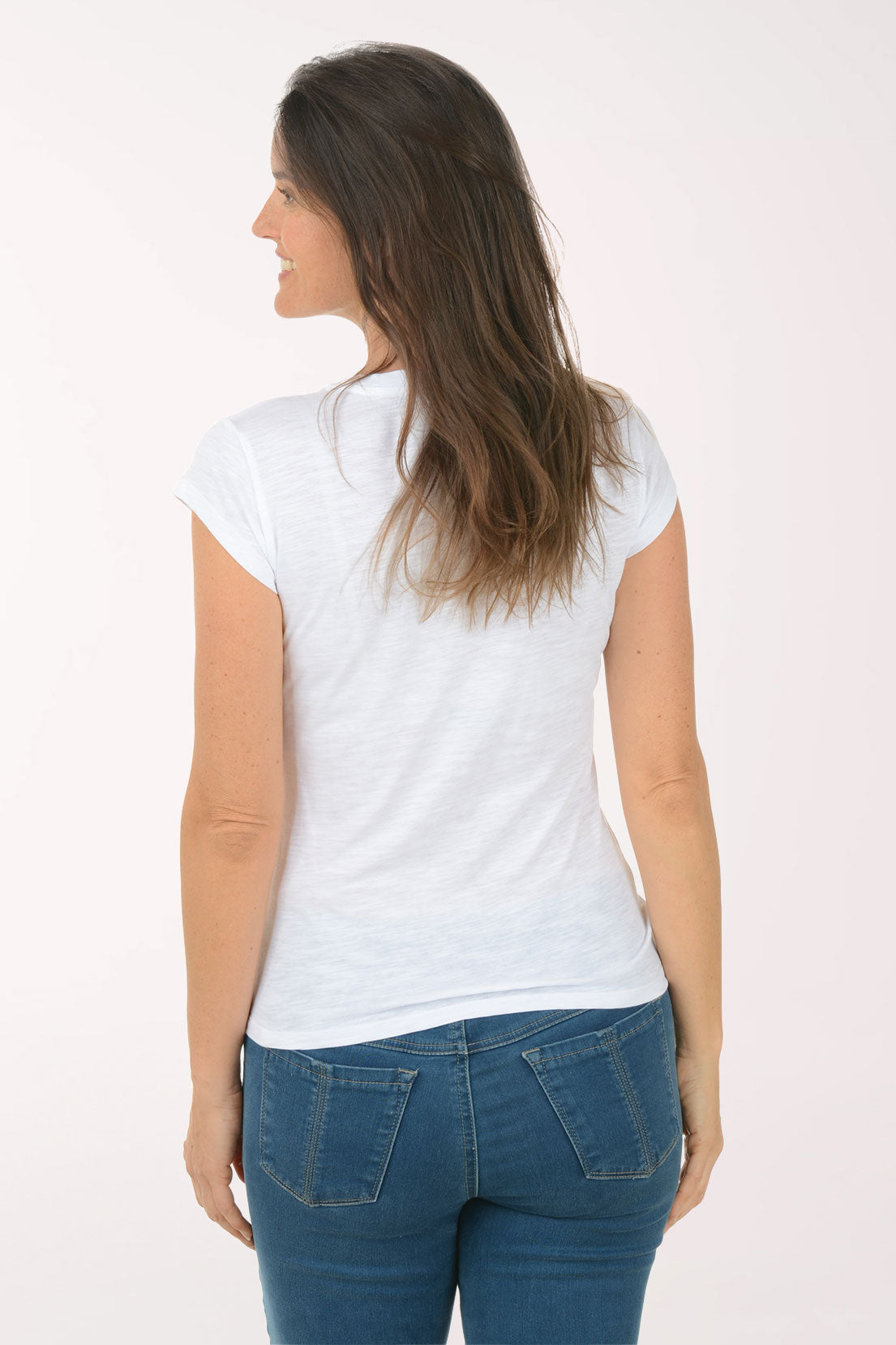 Woman wearing a white t-shirt with a blue heart design and blue jeans on a white background