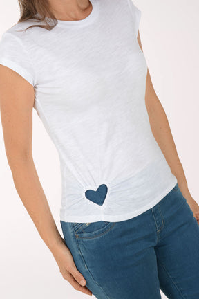Woman wearing a white t-shirt with a blue heart design and blue jeans on a white background