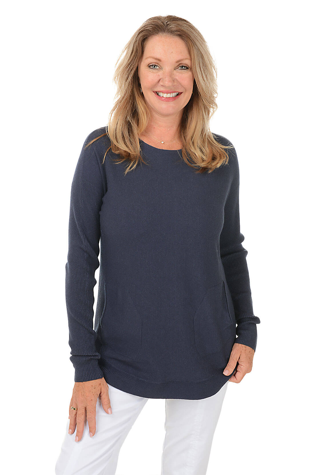 Woman wearing a navy blue sweater and white pants on a white background