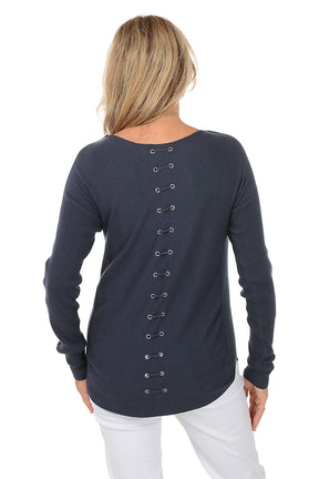 Woman wearing a navy blue sweater and white pants on a white background. Back shot.