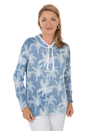 Woman wearing a blue hoodie with palm tree pattern on a white background
