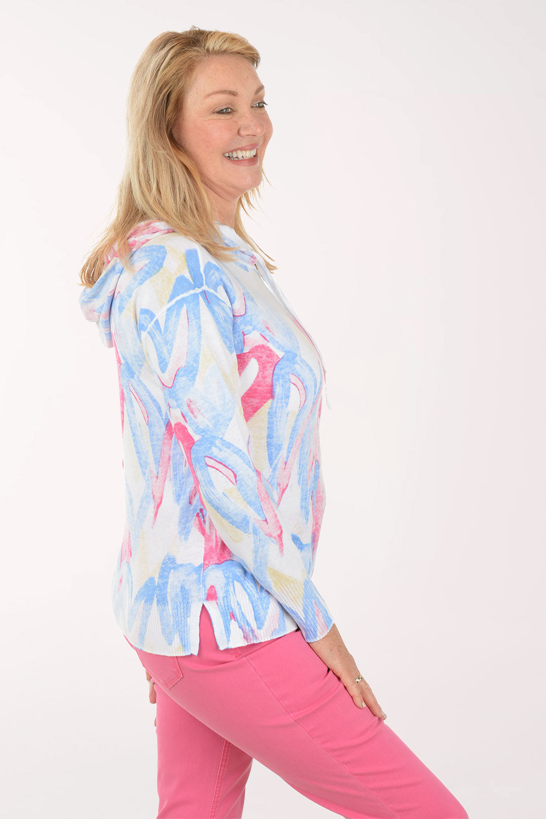 Woman wearing a colorful hoodie and pink pants on a white background