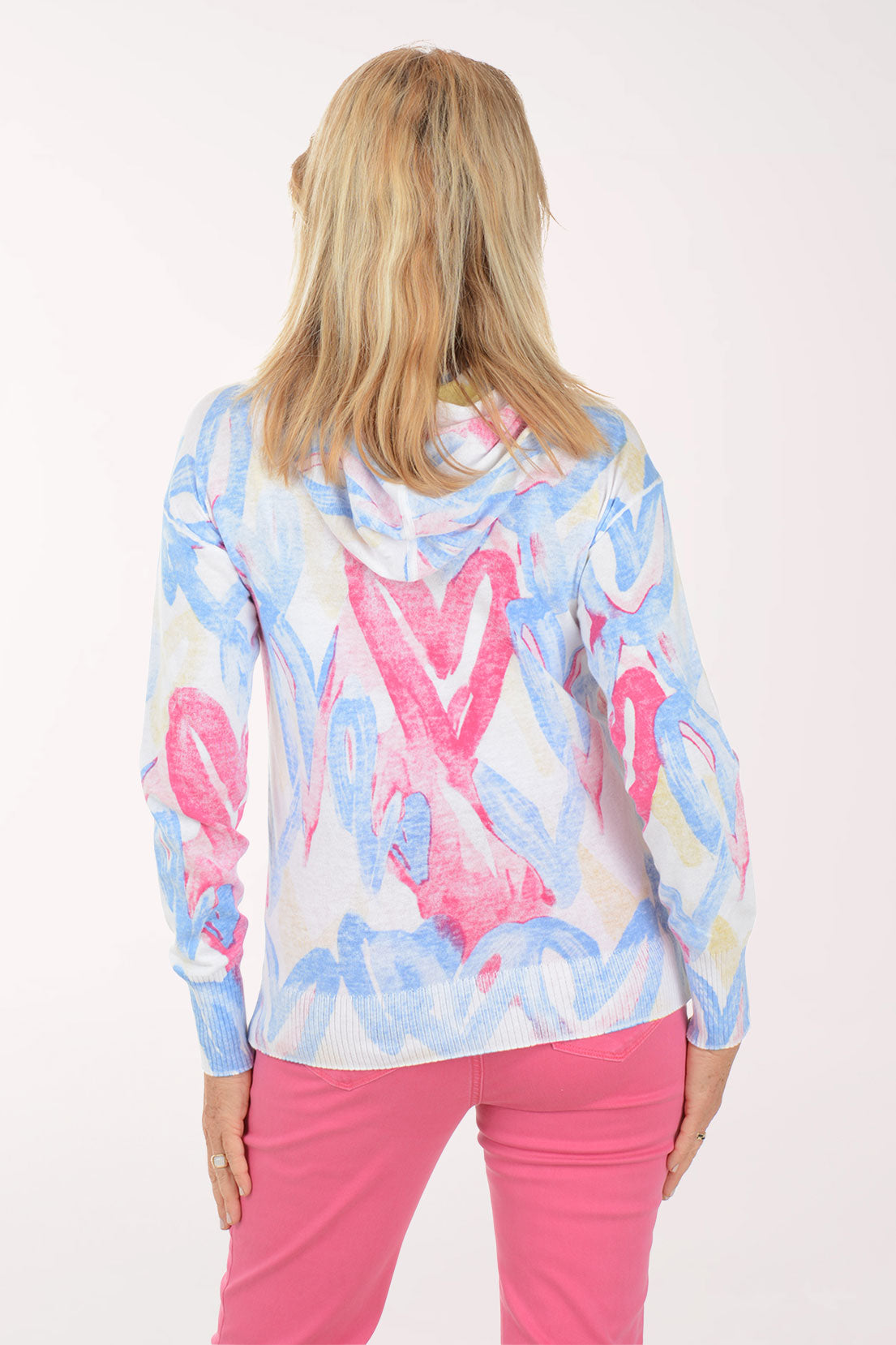 Woman wearing a colorful hoodie and pink pants on a white background