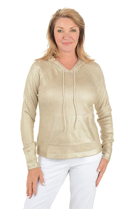 Woman wearing a gold hoodie and white pants on a white background.