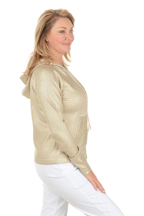 Woman wearing a gold hoodie and white pants on a white background. Side shot.