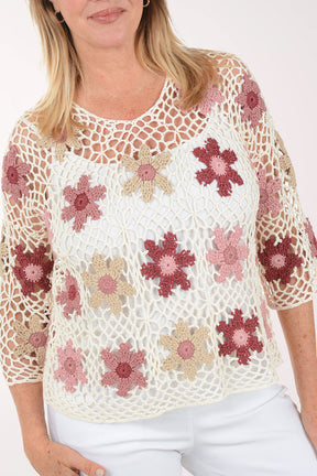 Woman wearing a floral crochet top on a white background