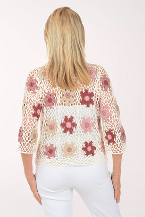 Woman wearing a floral crochet top on a white background