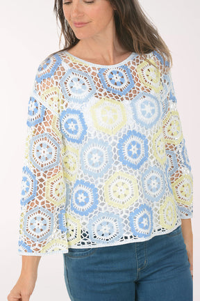 Woman wearing a colorful patterned top and blue jeans on a white background