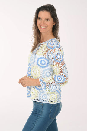 Woman wearing a colorful patterned top and blue jeans on a white background