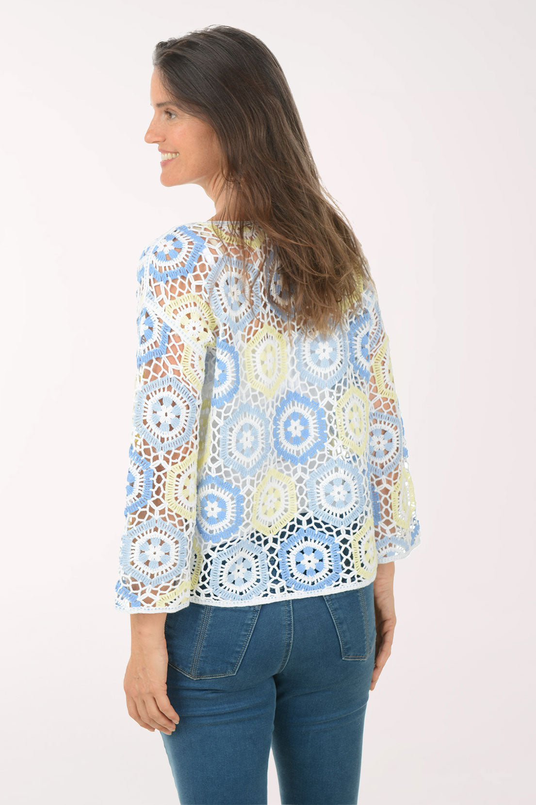Woman wearing a colorful patterned top and blue jeans on a white background