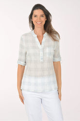 Woman wearing a light-colored blouse with rolled-up sleeves on a white background