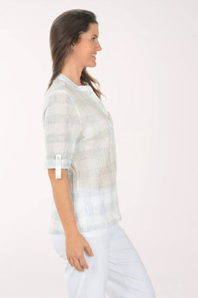 Woman wearing a light-colored blouse with rolled-up sleeves on a white background