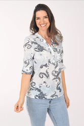 Woman wearing a light blue patterned blouse with rolled-up sleeves on a white background