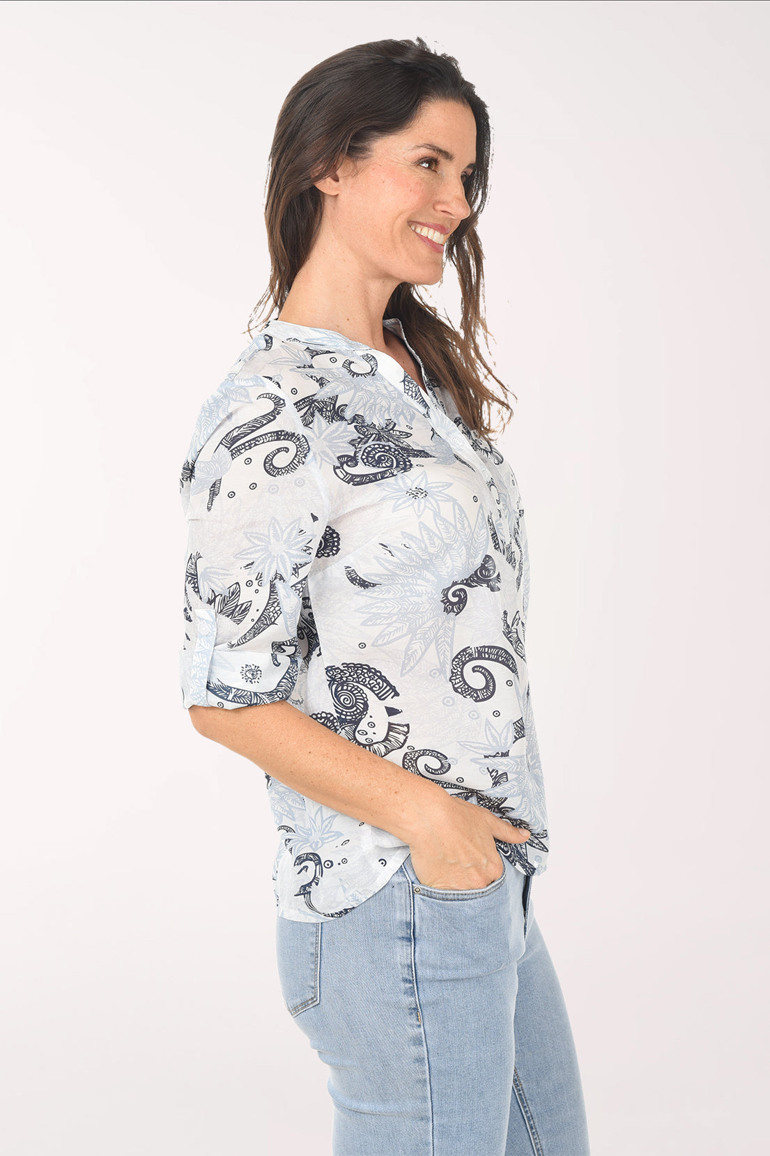 Woman wearing a light blue patterned blouse with rolled-up sleeves on a white background