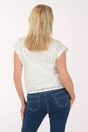Woman wearing a white lace top and blue jeans on a white background