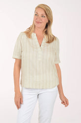 Woman wearing a light-colored striped shirt and white pants on a white background