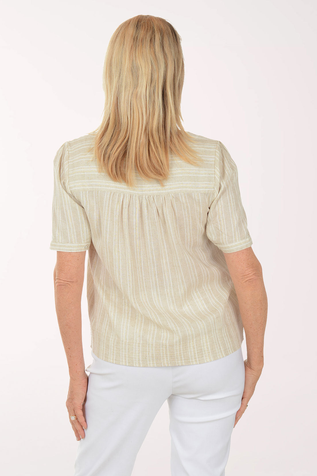 Woman wearing a light-colored striped shirt and white pants on a white background