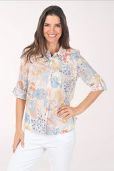 Woman wearing a floral blouse with white pants on a white background