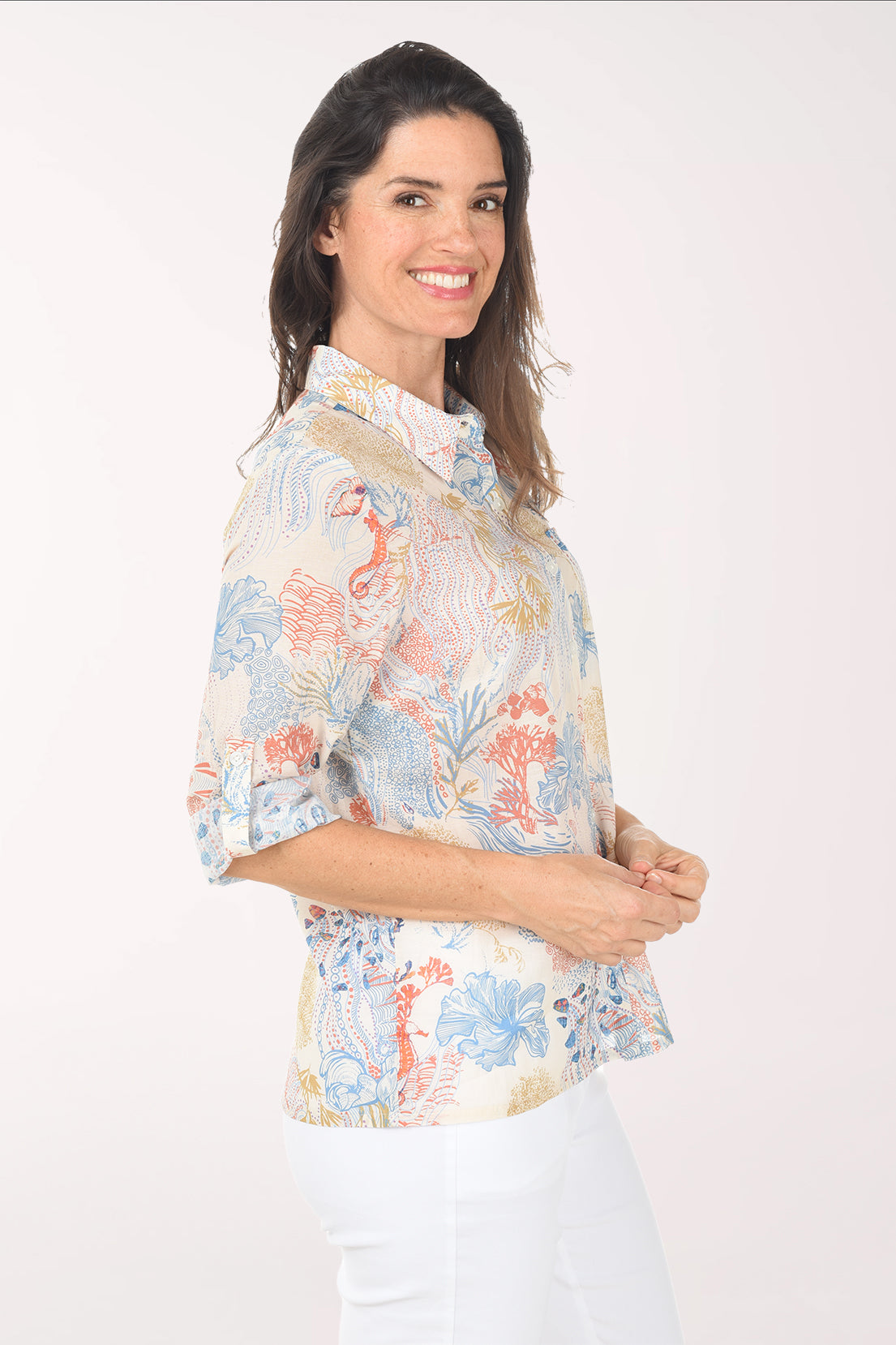 Woman wearing a floral blouse with white pants on a white background