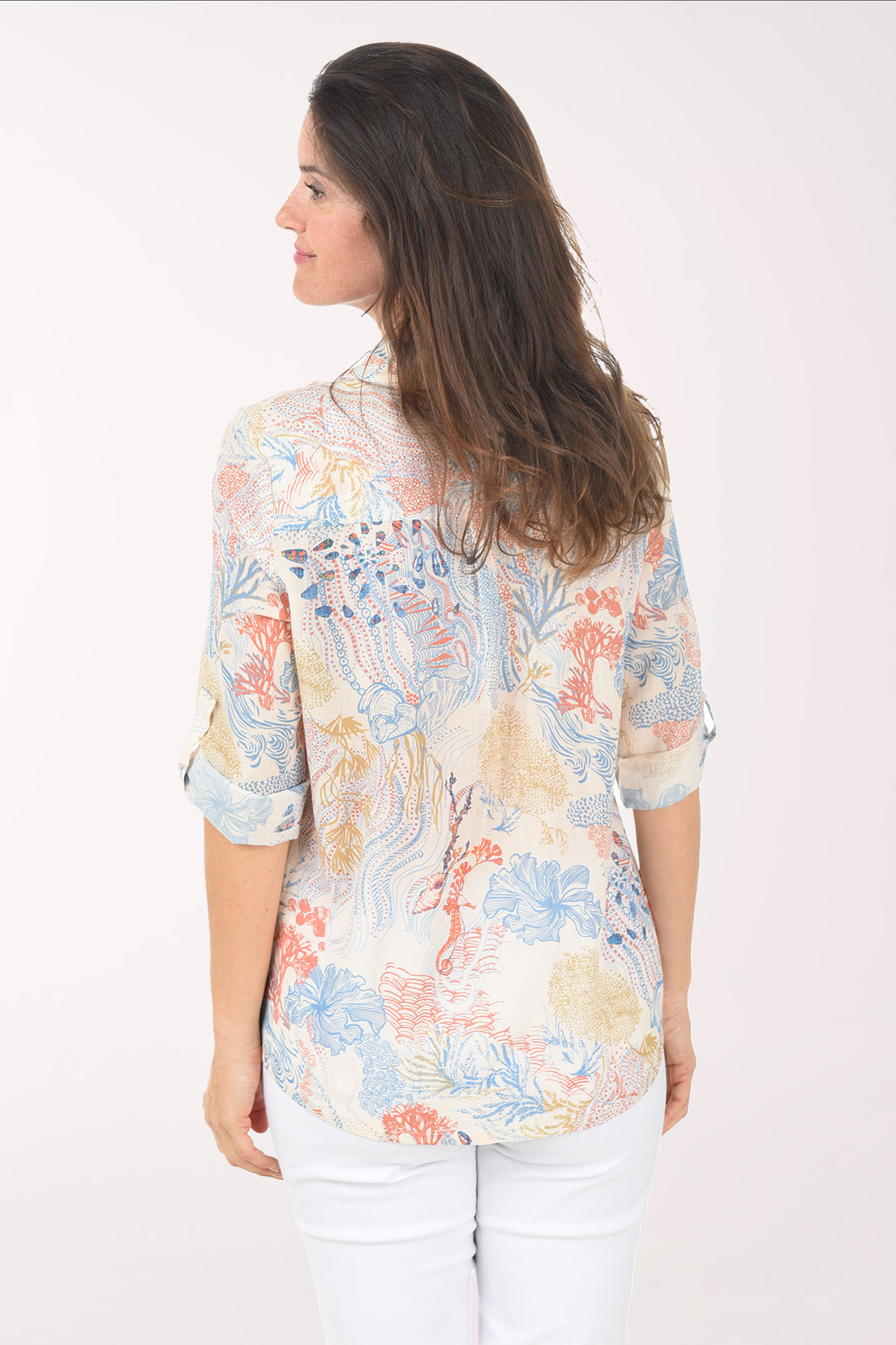 Woman wearing a floral blouse with white pants on a white background