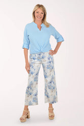 Woman wearing a light blue top and floral pants on a white background