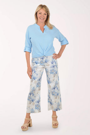 Woman wearing a light blue top and floral pants on a white background