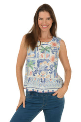 Woman wearing a sleeveless floral top with palm trees and blue jeans on a white background
