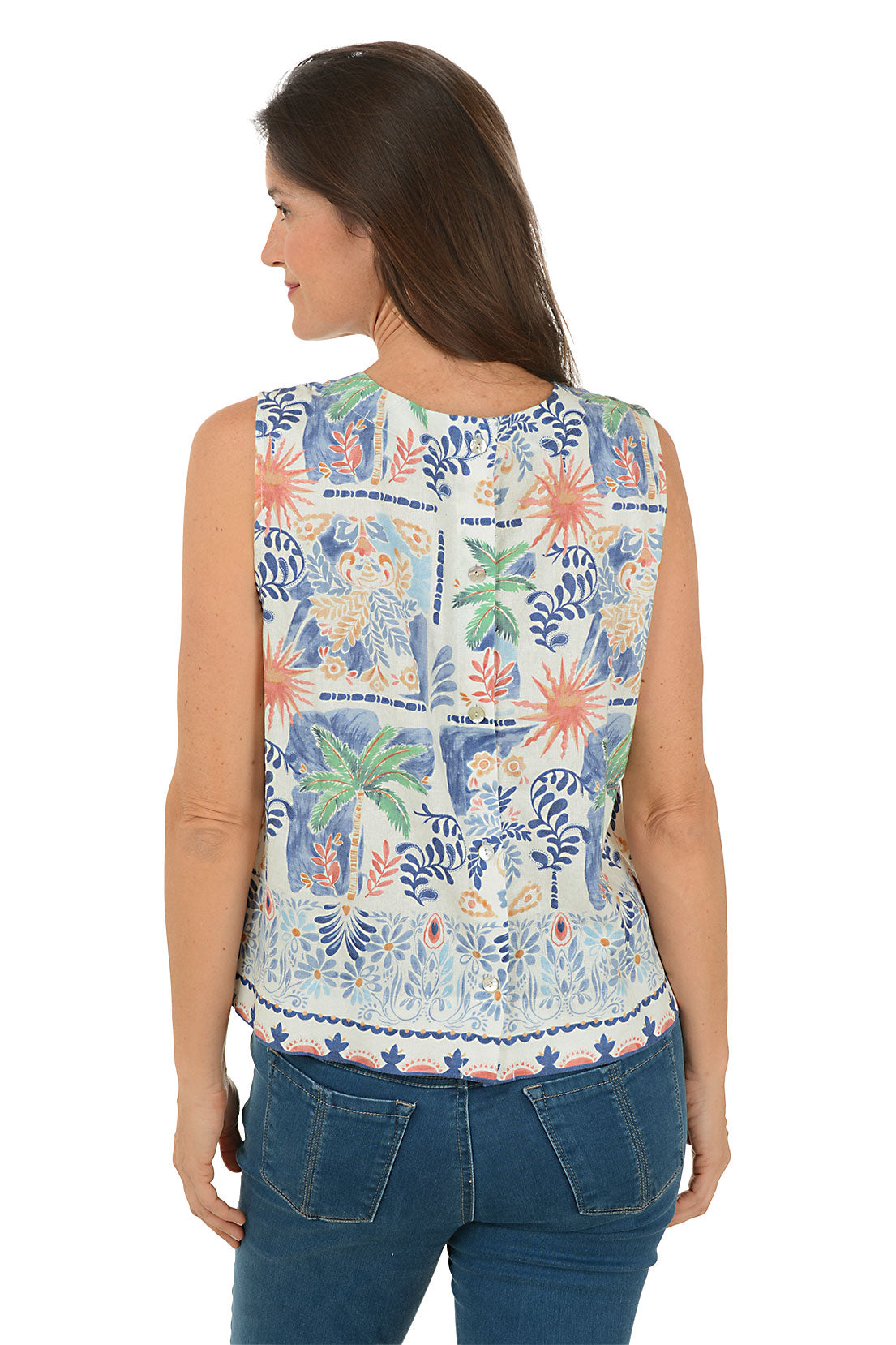 Woman wearing a sleeveless floral top with palm trees and blue jeans on a white background
