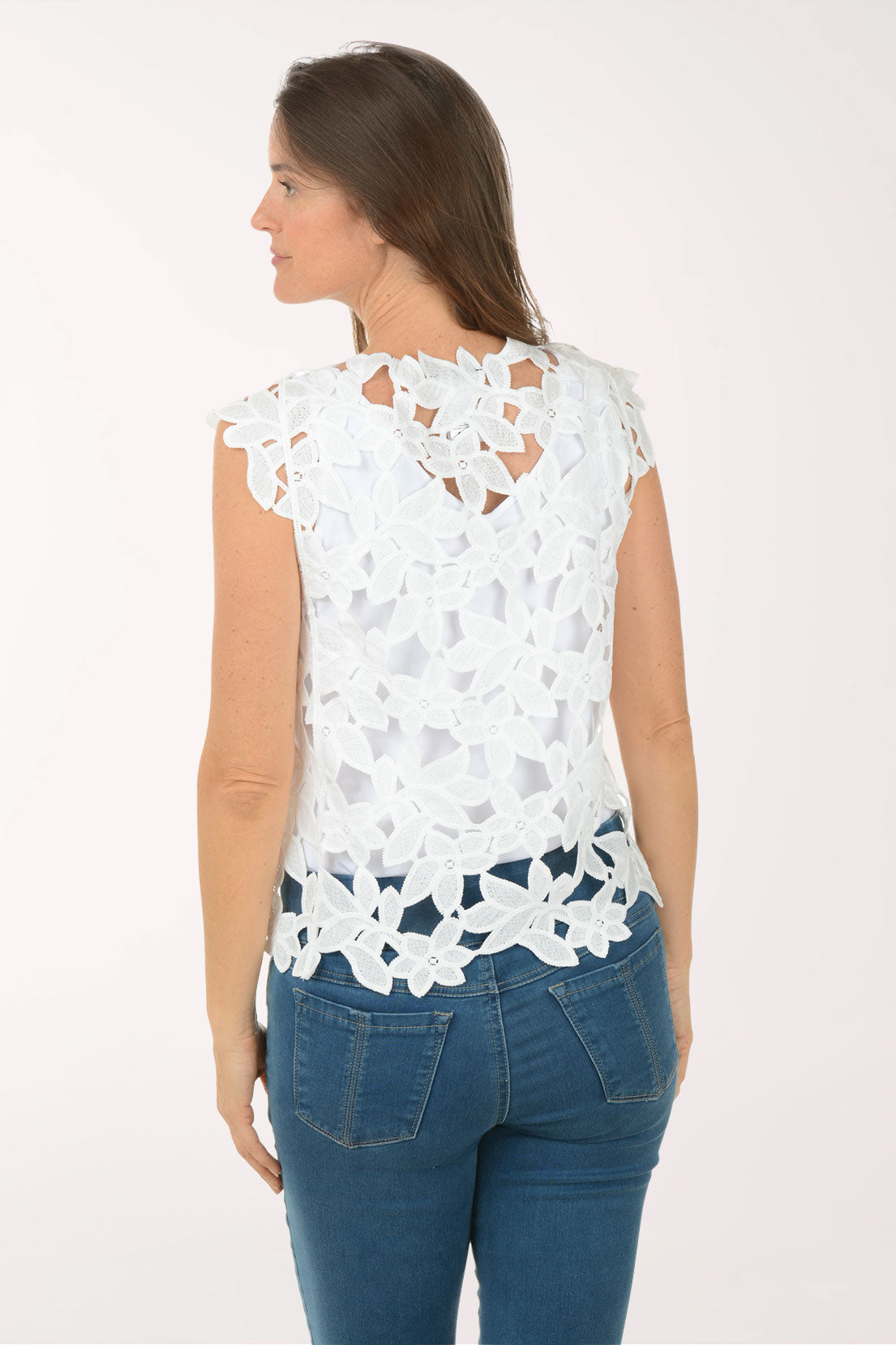 Woman wearing a white lace top and blue jeans on a white background