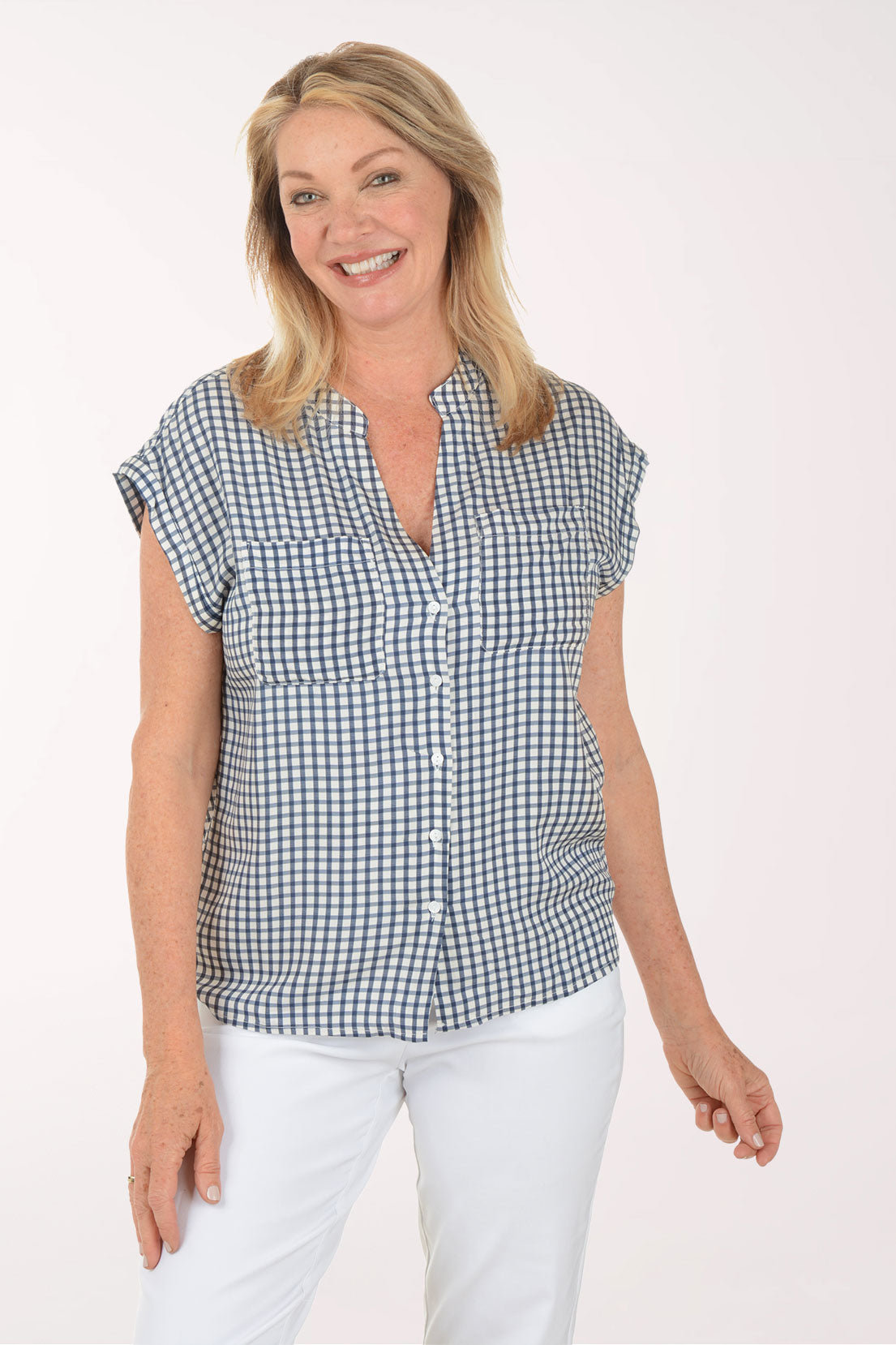 Woman wearing a black and white checkered shirt with white pants on a white background