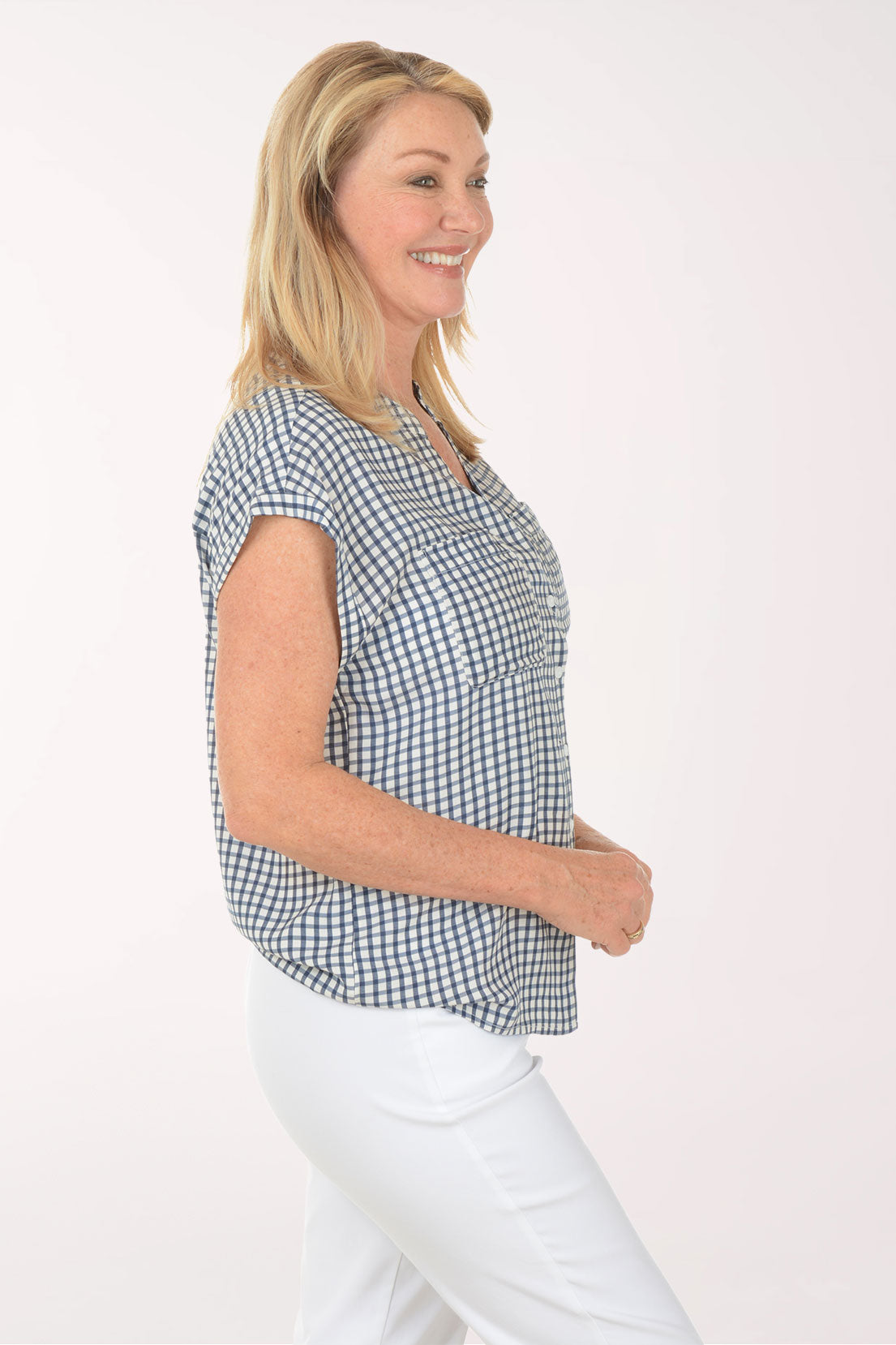 Woman wearing a black and white checkered shirt with white pants on a white background