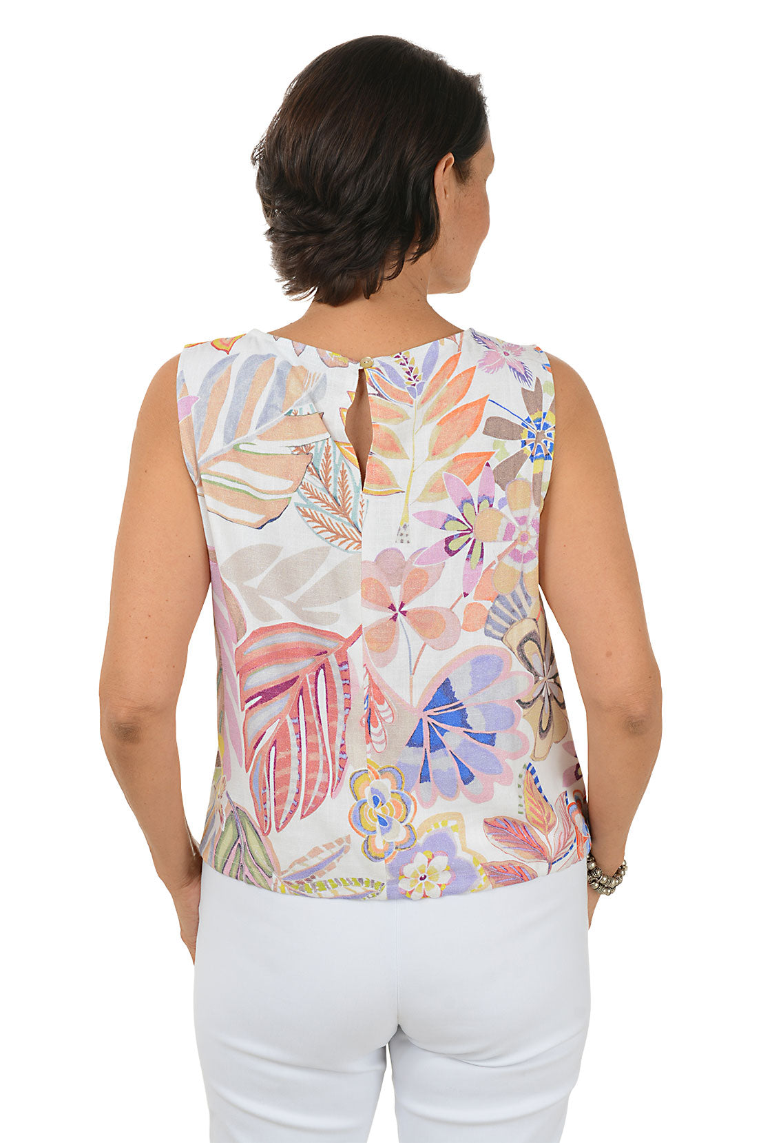 Woman wearing a sleeveless floral top and white pants on a white background