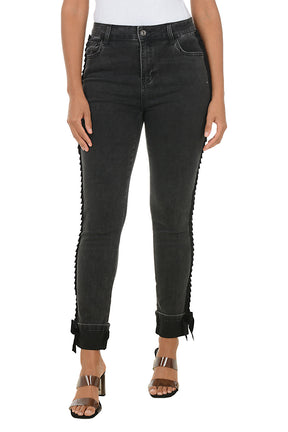 Person wearing black jeans with ruffled edges on a white background.