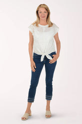 Woman wearing a white lace top and blue jeans on a white background