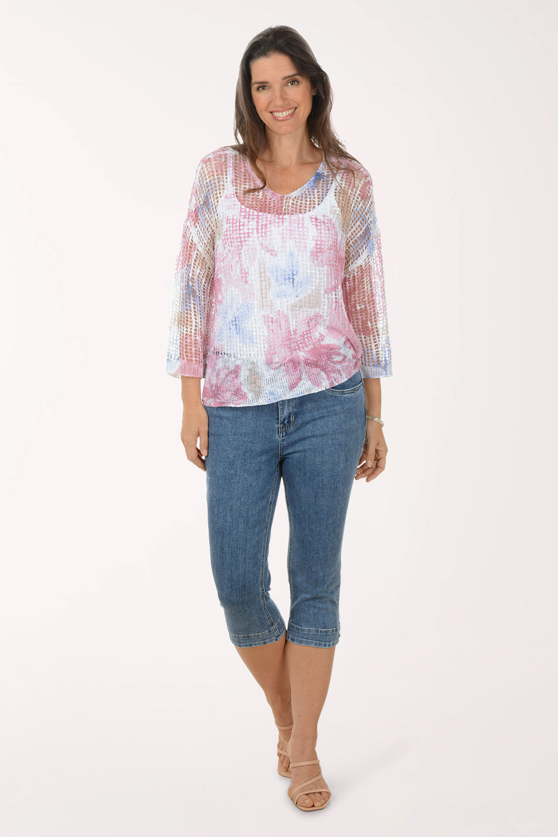 Woman wearing a floral blouse and blue jeans on a white background