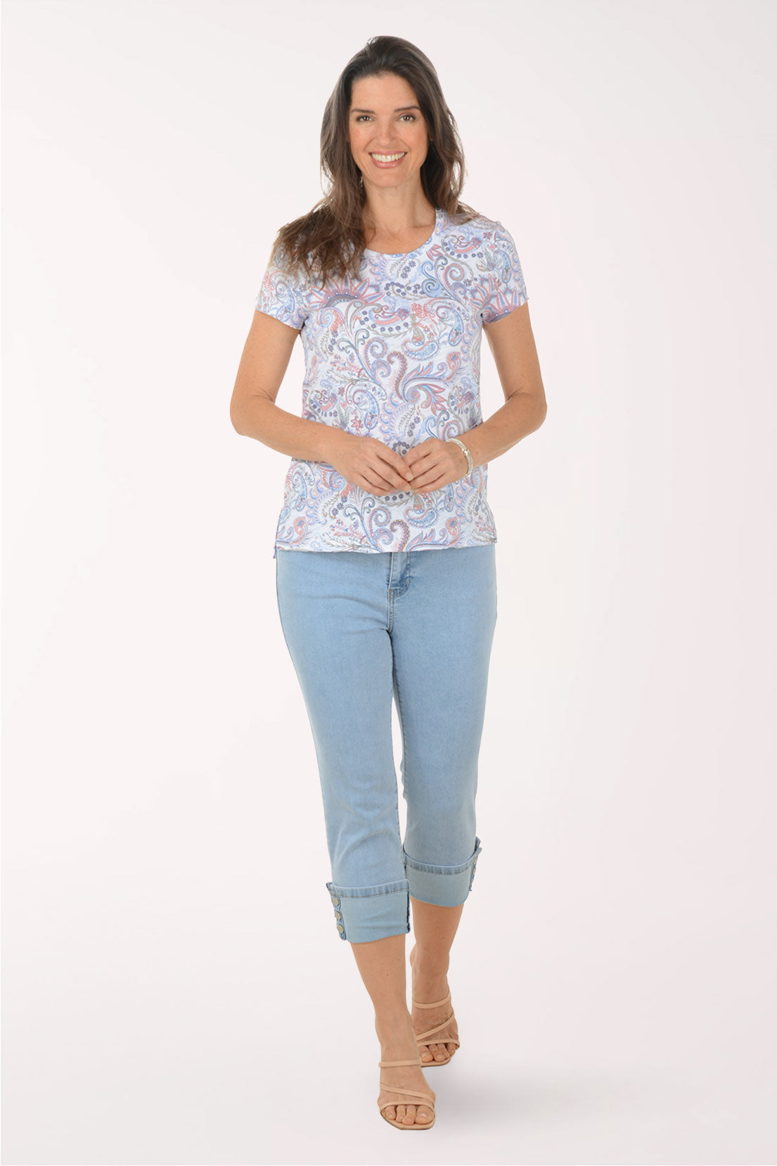 Woman wearing a patterned top and light blue jeans on a white background