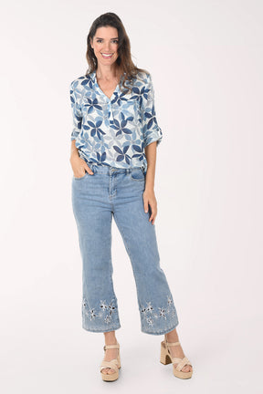 Light blue jeans with floral embroidery at the bottom worn by a person on a white background