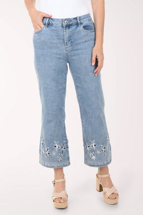 Light blue jeans with floral embroidery at the bottom worn by a person on a white background