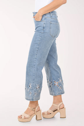 Light blue jeans with floral embroidery at the bottom worn by a person on a white background