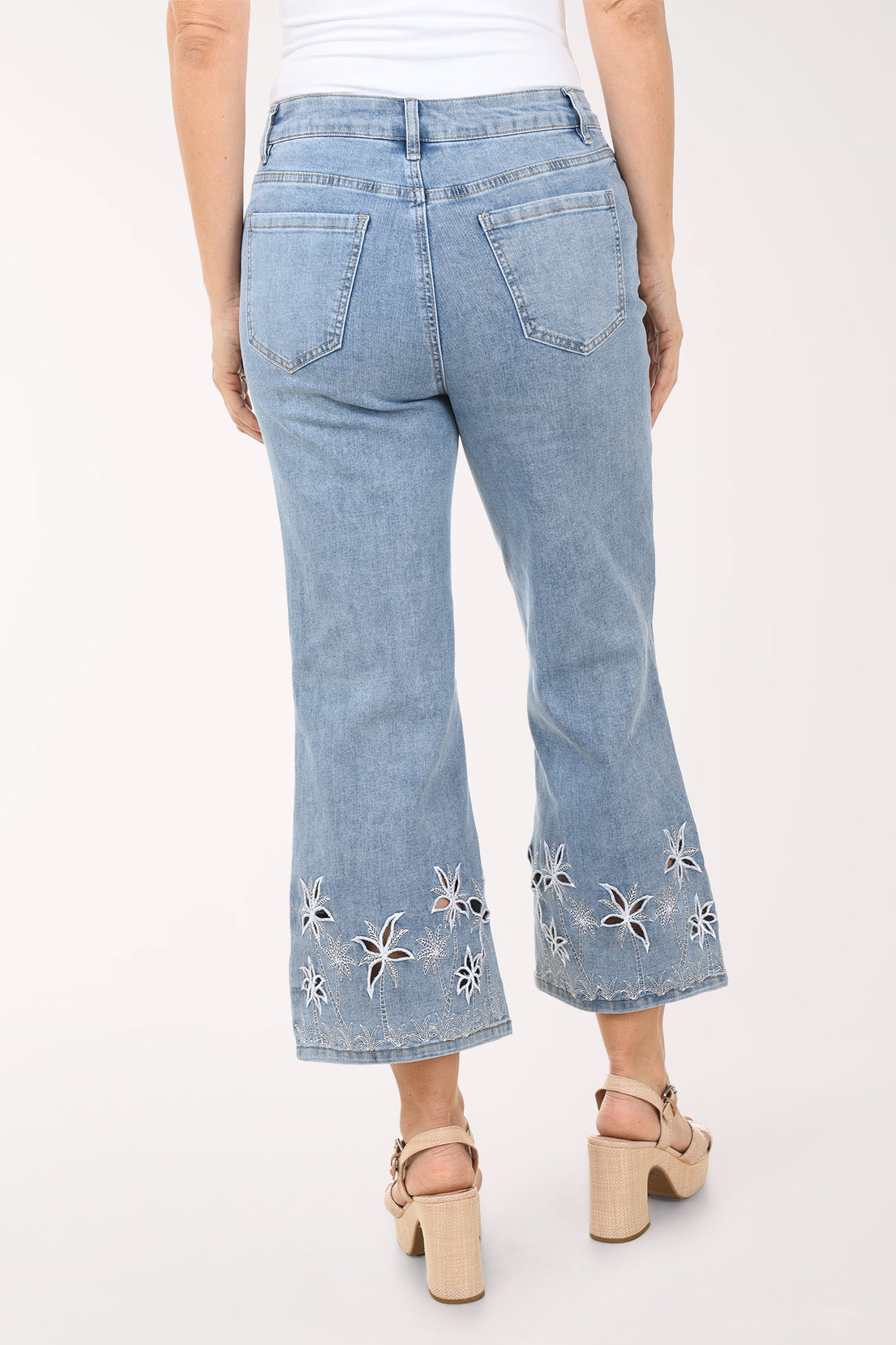 Light blue jeans with floral embroidery at the bottom worn by a person on a white background