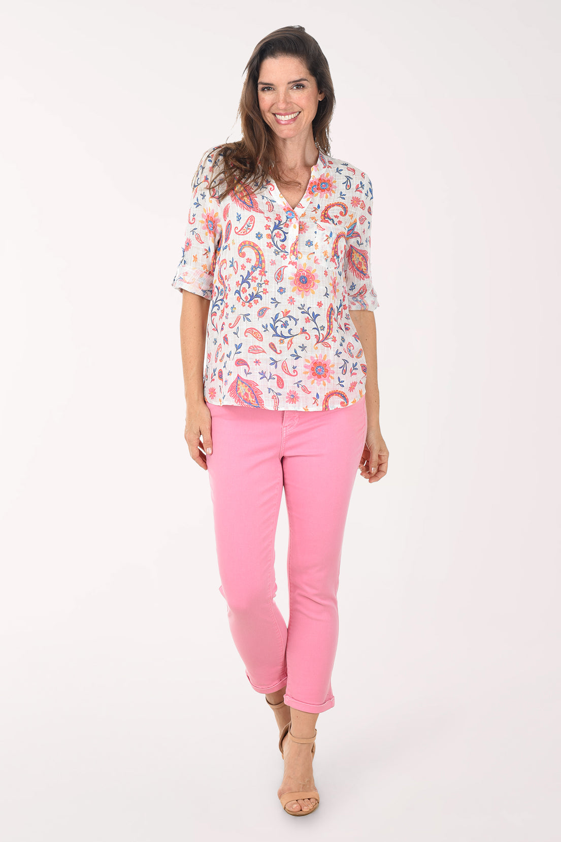 Woman wearing a floral blouse and pink pants on a white background