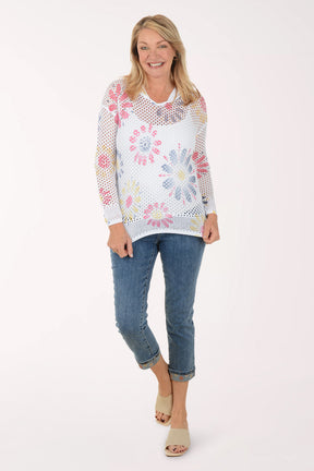 Woman wearing a colorful floral-patterned sweater and jeans on a white background