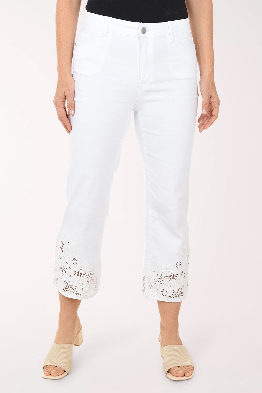Woman wearing a blue and white patterned top with white pants on a white background